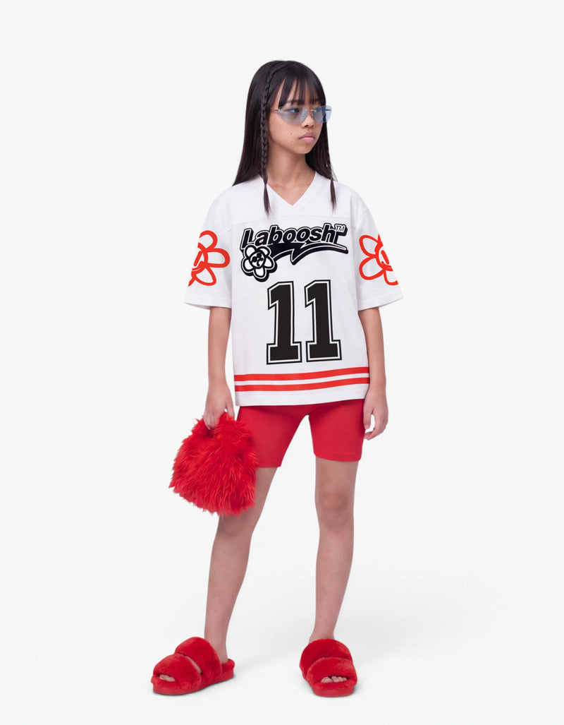 Girl in white baseball tee from 11:11 Make a Wish, front view, with a signature Laboosh™ print, on a white studio backdrop. — alt view