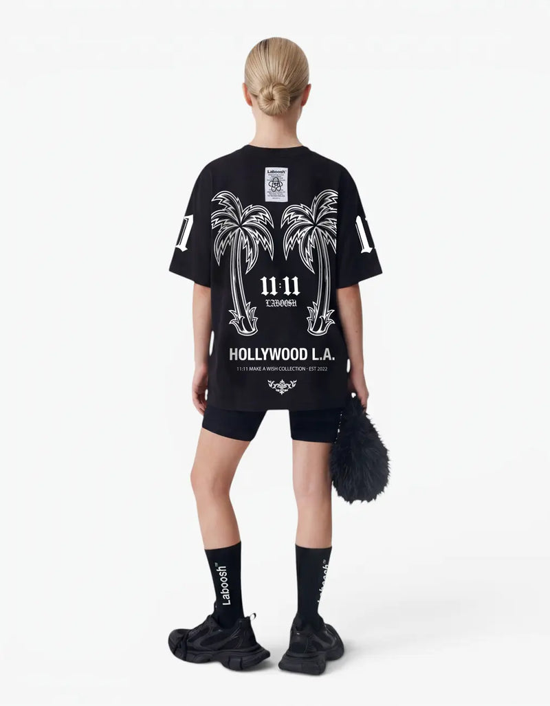 Girl wearing black t-shirt, back view, with a signature Laboosh™ print, against a bright white background. — alt view