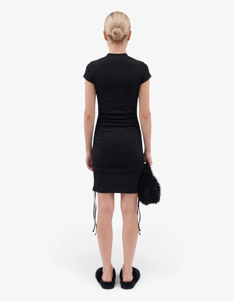 Back view of a black ribbed ruched dress with short sleeves for girls, worn by a model on a white background — alt view