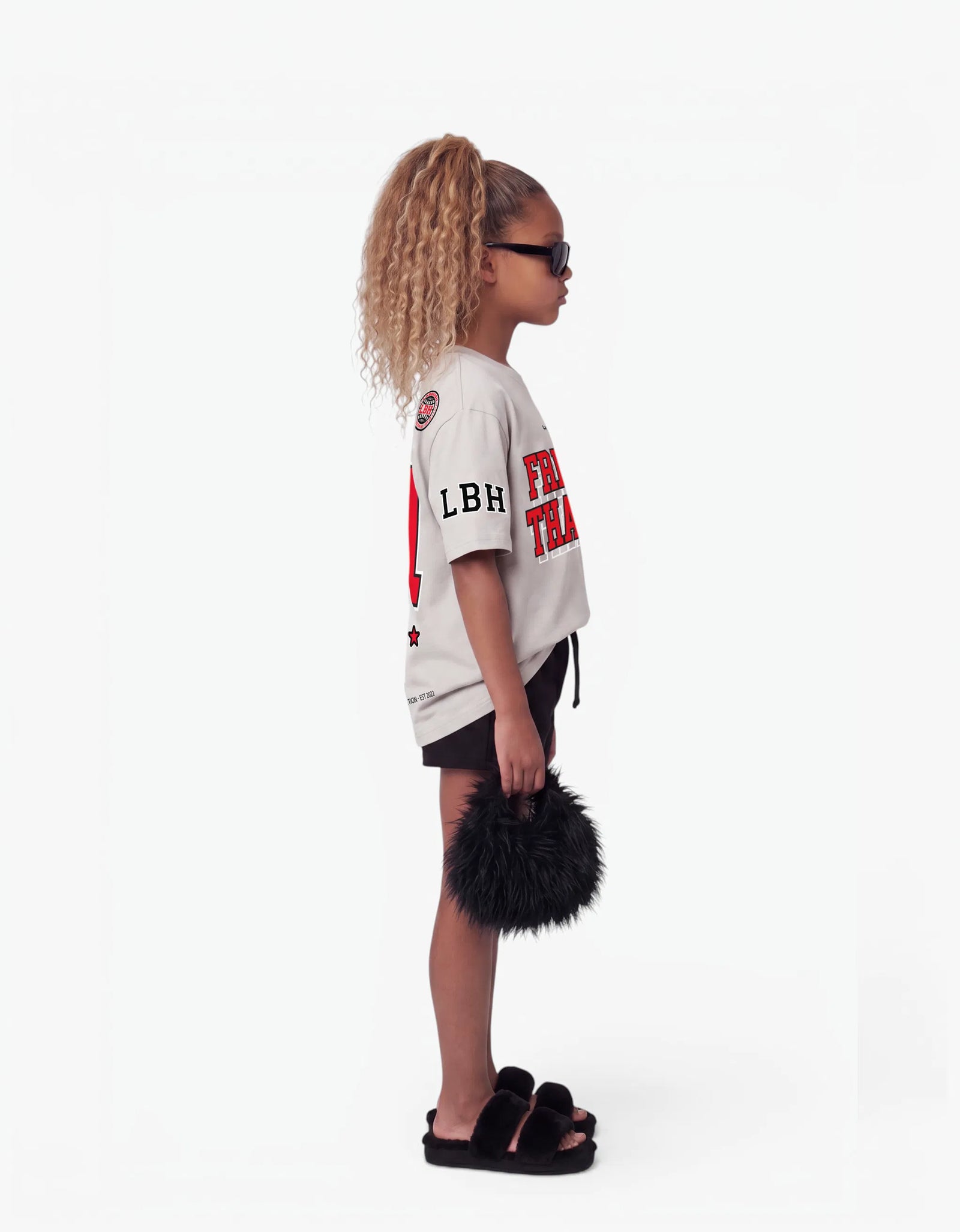 Girl in cream t-shirt from Rib Collection, side view, with a signature Laboosh™ print, photographed on a plain white background.