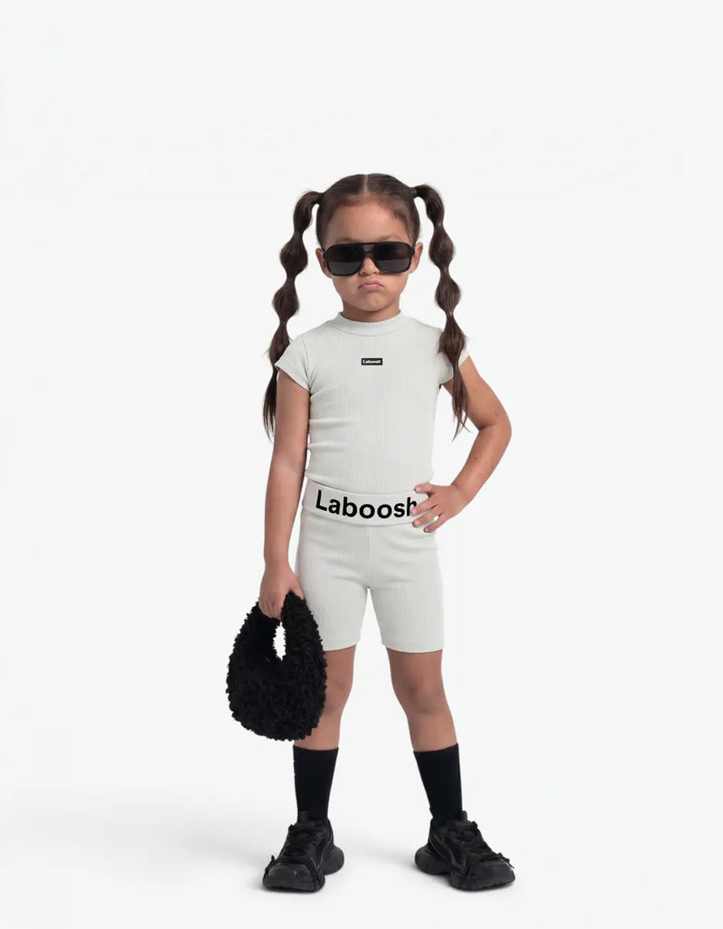 Girl modelling Grey ribbed two-piece set, front view, Laboosh™ detail on the chest, on a white background.