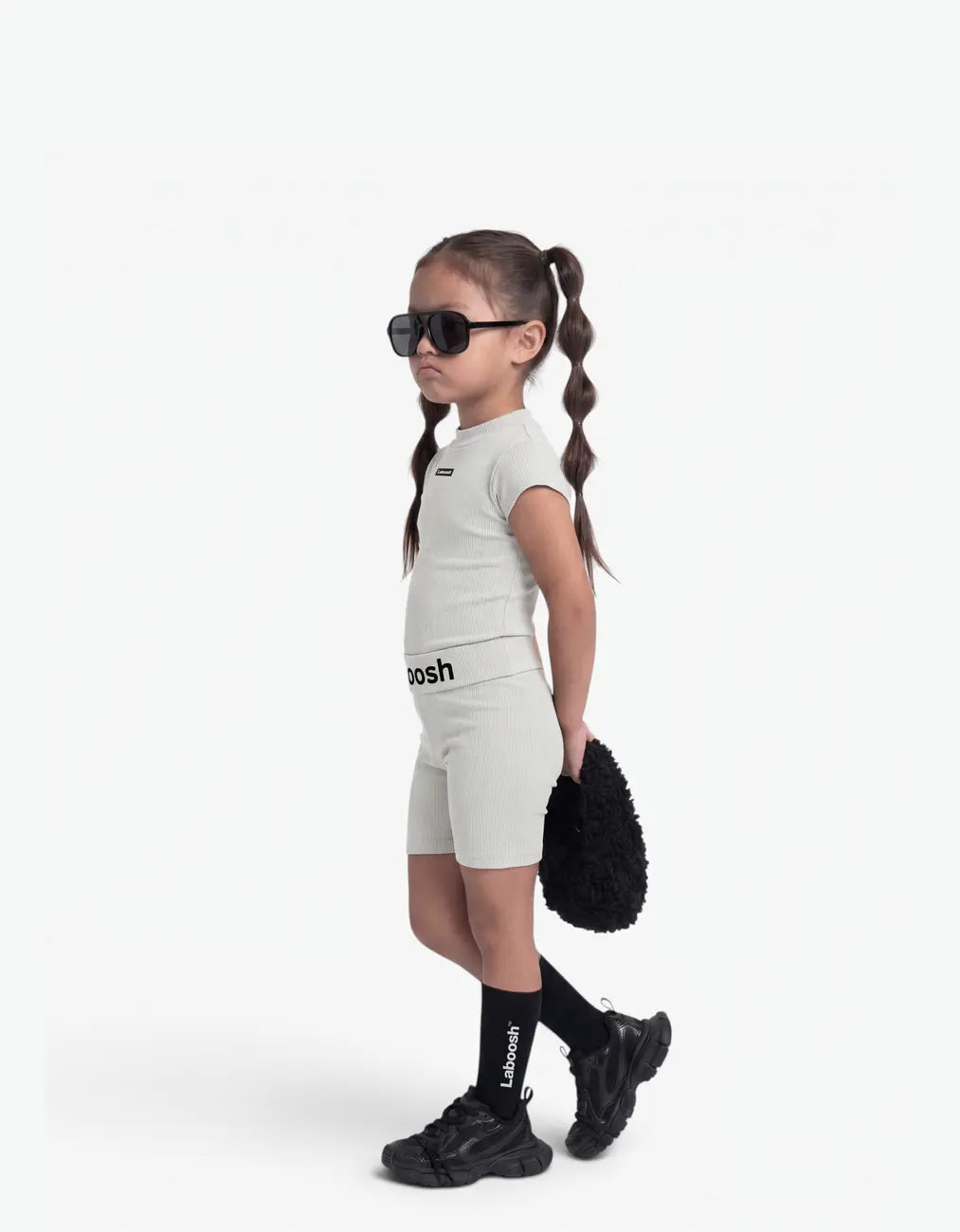 Girl wearing Grey ribbed two-piece set, side view, with Laboosh™ branding on the chest, shown with coordinating MoodSwings staples.