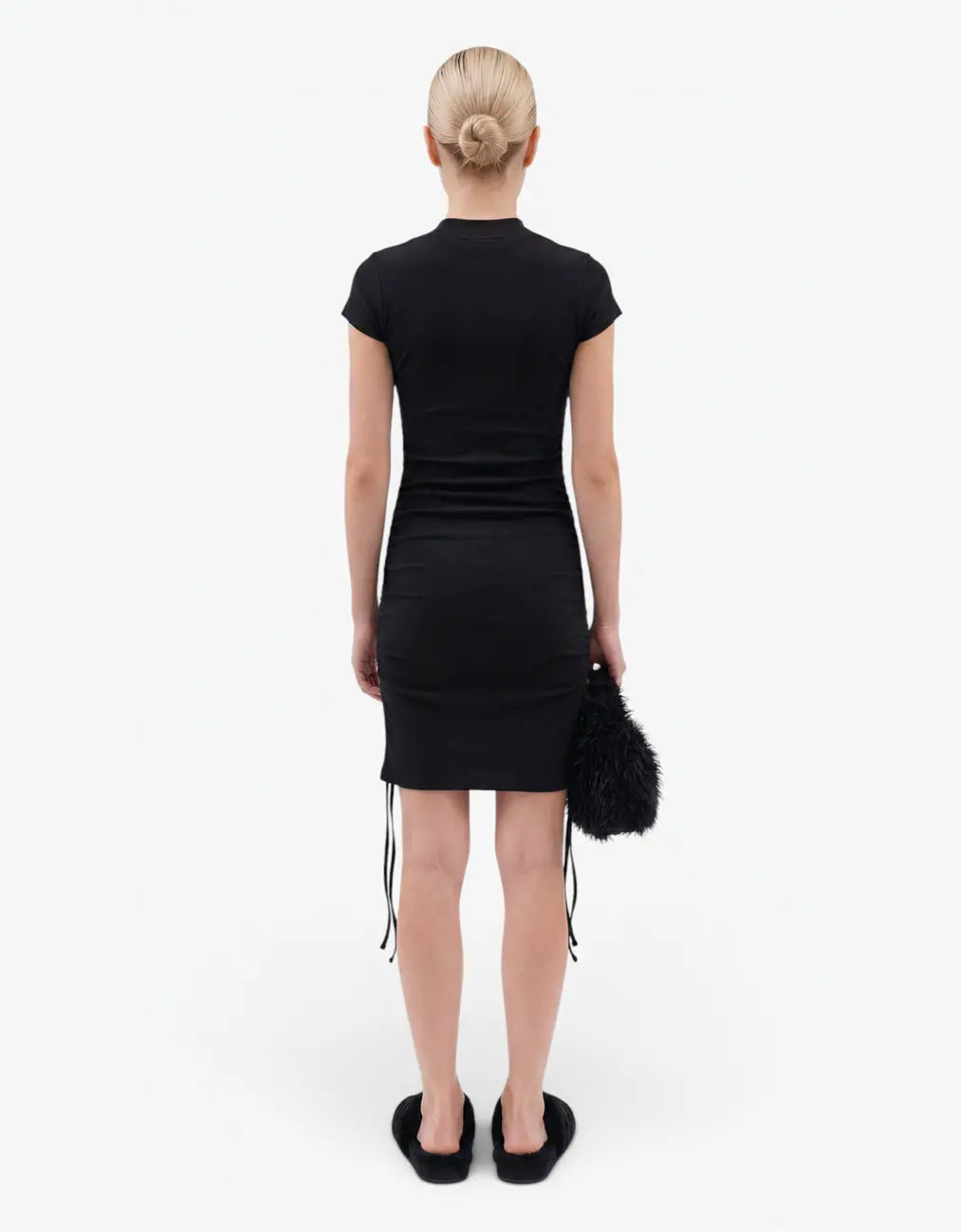 Back view of a black ribbed ruched dress with short sleeves for girls, worn by a model on a white background