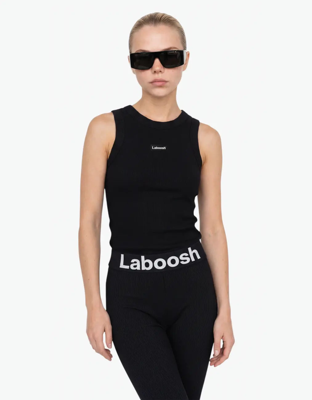 Black ribbed tank top for girls by Laboosh™, half-body close-up showing the sleeveless ribbed-knit fit and Laboosh™ logo on the chest, paired with a Laboosh™ logo waistband on a white background