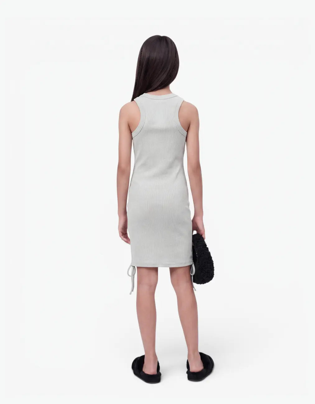 Back view of a girl wearing the grey ribbed ruched dress, showing the fitted sleeveless ribbed back and ruched hem ties, on a white background