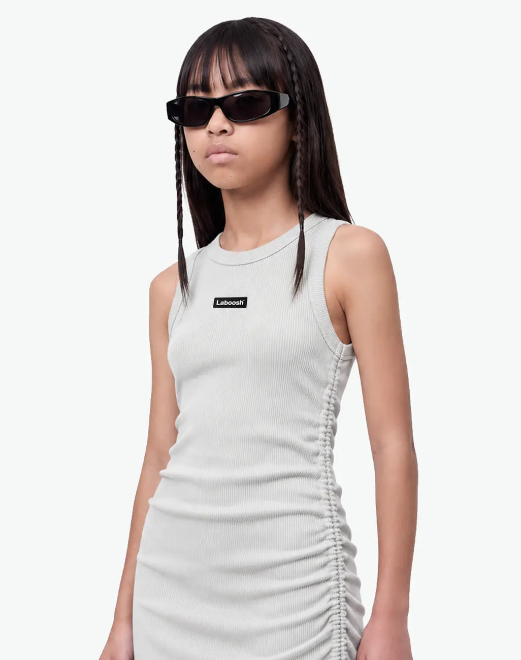 Girl wearing the grey ribbed ruched dress, half-body view, showing the sleeveless fit and the Laboosh™ logo on the chest, on a white background