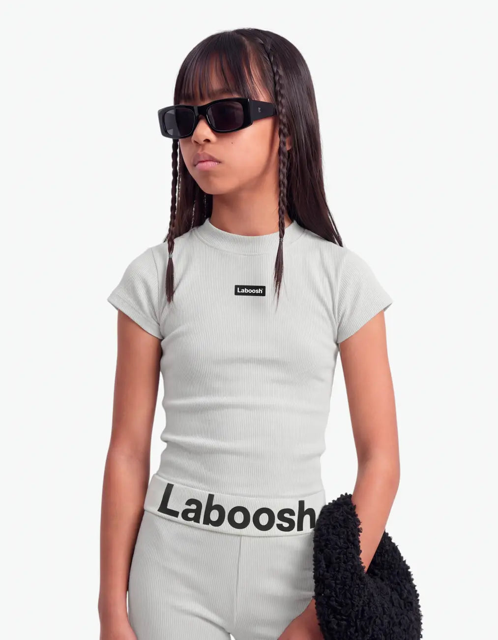 Girl in grey ribbed short sleeve top from Rib Collection, half-body view, with the Laboosh™ logo on the chest, photographed on a plain white background.
