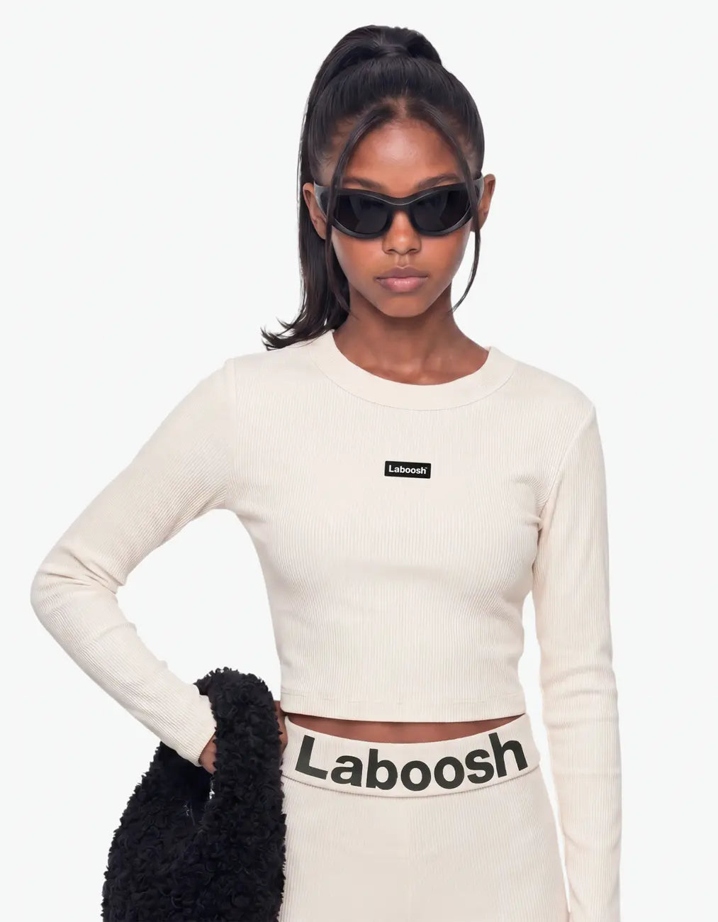 Cream ribbed long leggings for girls, close-up of the bold Laboosh™ logo on the waistband, worn with a matching ribbed crop top, on a white background