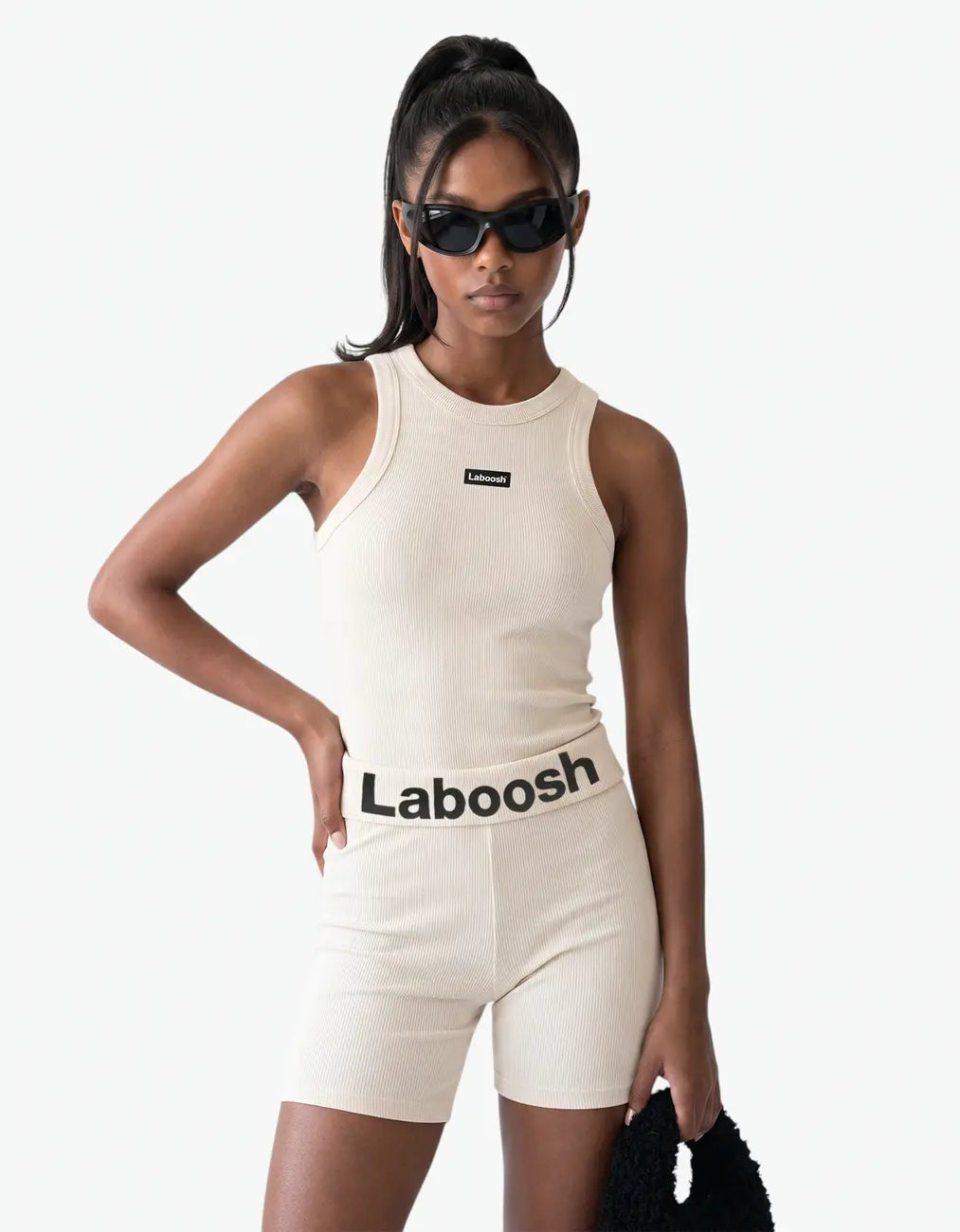 Cream ribbed tank top for girls by Laboosh™, half-body close-up showing the sleeveless ribbed-knit fit and Laboosh™ logo on the chest, paired with a Laboosh™ logo waistband on a white background